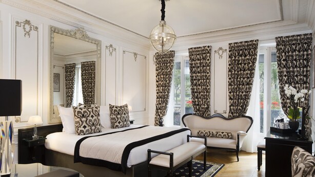 Een hotelkamer met een groot bed, een bank, een bureau en een spiegel.