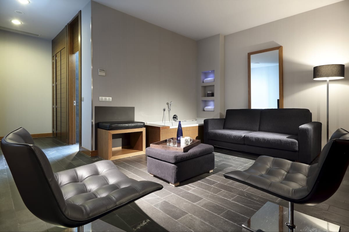 Ein modernes Wohnzimmer mit einer Couch, zwei Sesseln, einem Couchtisch und einem kleinen Beistelltisch.