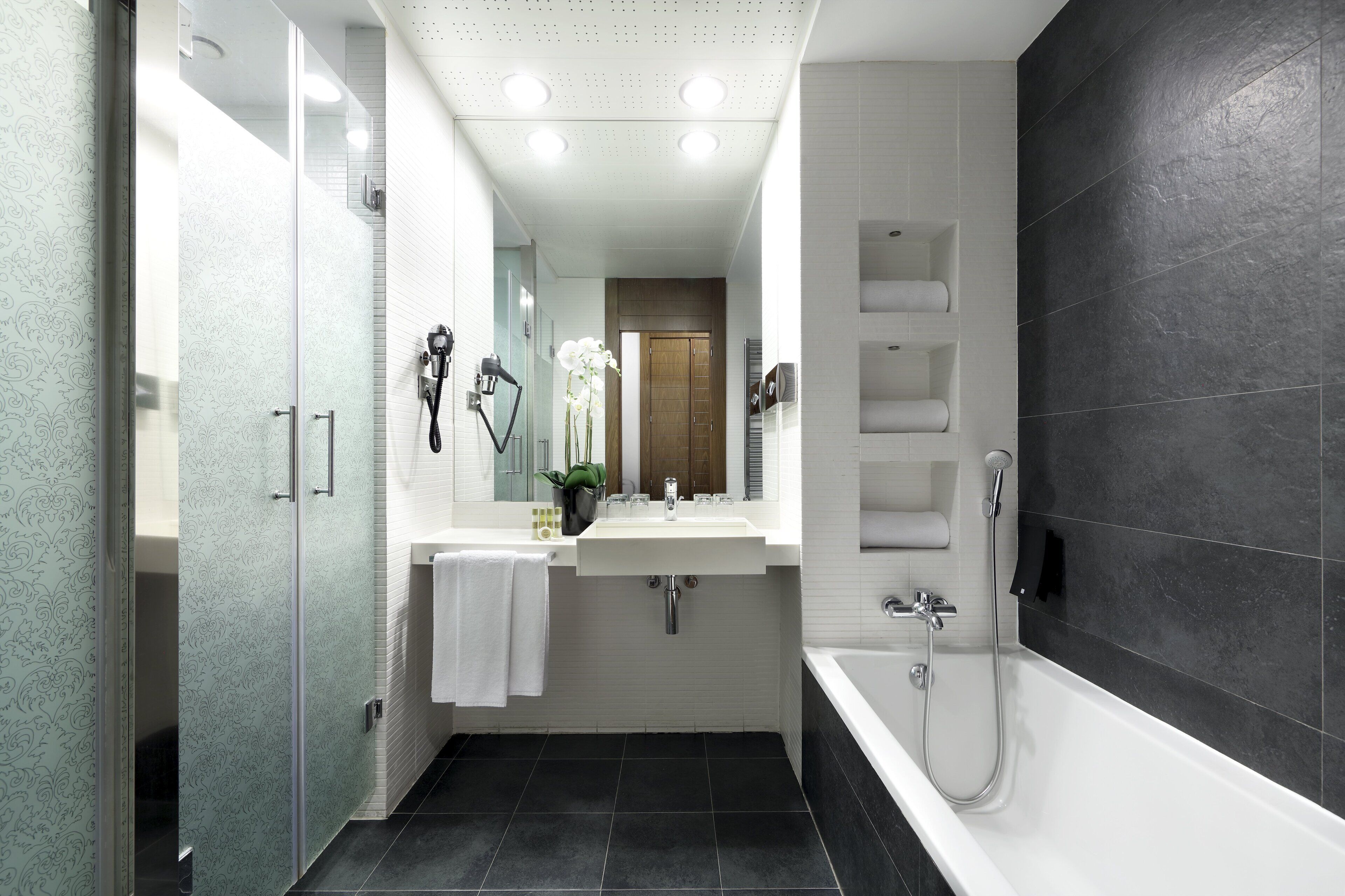 Un bagno moderno con doccia vetrata, lavabo bianco e vasca da bagno.