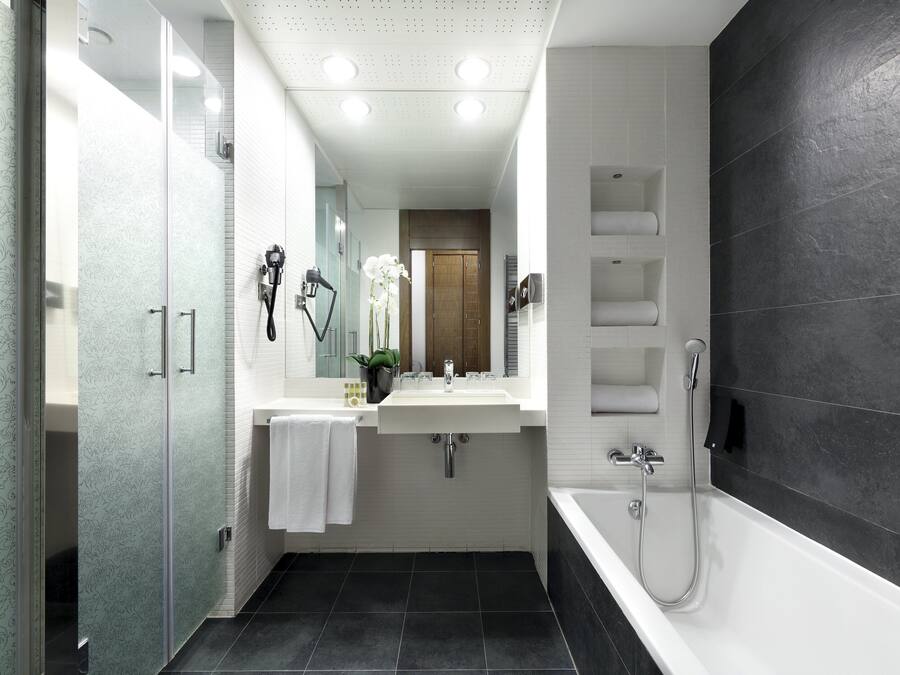 Un baño moderno con cabina de ducha de vidrio, lavabo blanco y bañera.