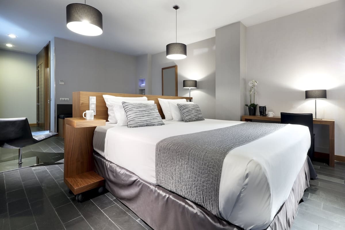 Ein modernes Hotelzimmer mit einem großen Bett, Nachttischen, einem Schreibtisch und einem Stuhl.