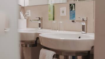 A bathroom with two sinks, a towel hanging, and a mirror.