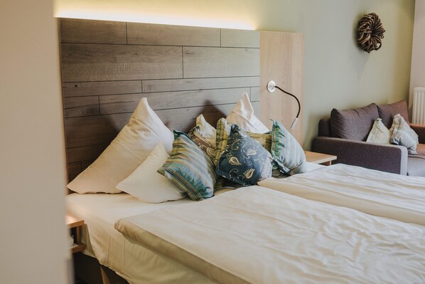 Una habitación de hotel con cabecera de madera, una cama con muchas almohadas y una mesita de noche.