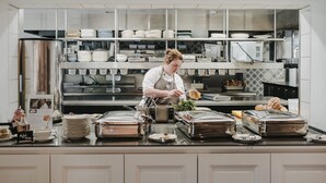 A chef preparing food in a modern kitchen with stainless steel appliances and neatly organized shelves. - Landhotel Saarschleife (Mettlach)