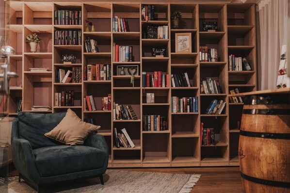 Un coin lecture confortable avec une bibliothèque, un fauteuil bleu et un tonneau en bois.
