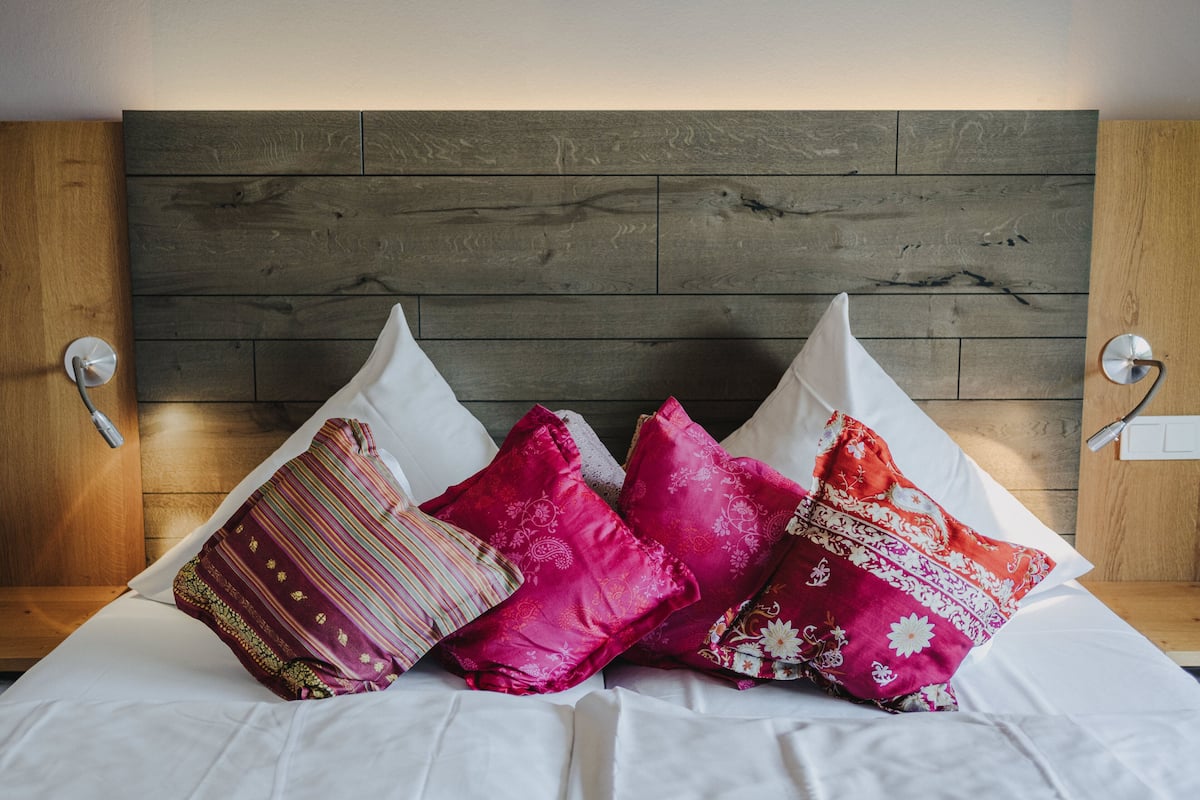A bed with white bedding and multiple decorative pillows in various patterns and colors.