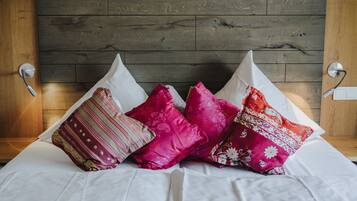 A bed with white bedding and multiple decorative pillows in various patterns and colors.