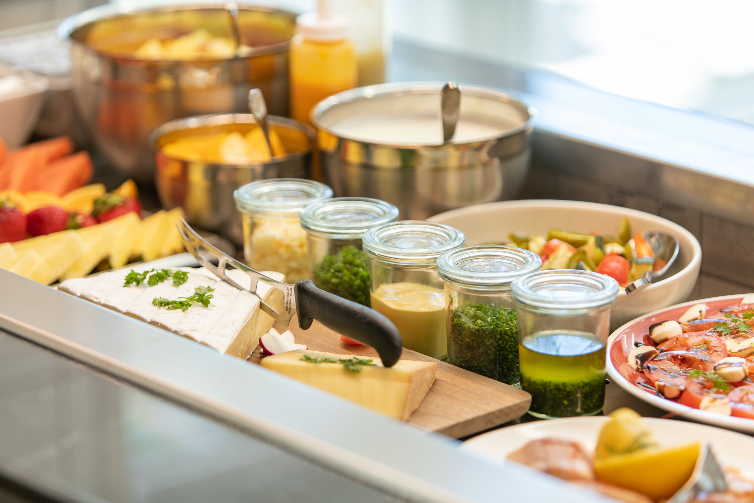 Un bufé con diversos alimentos, incluyendo queso, frutas y verduras.