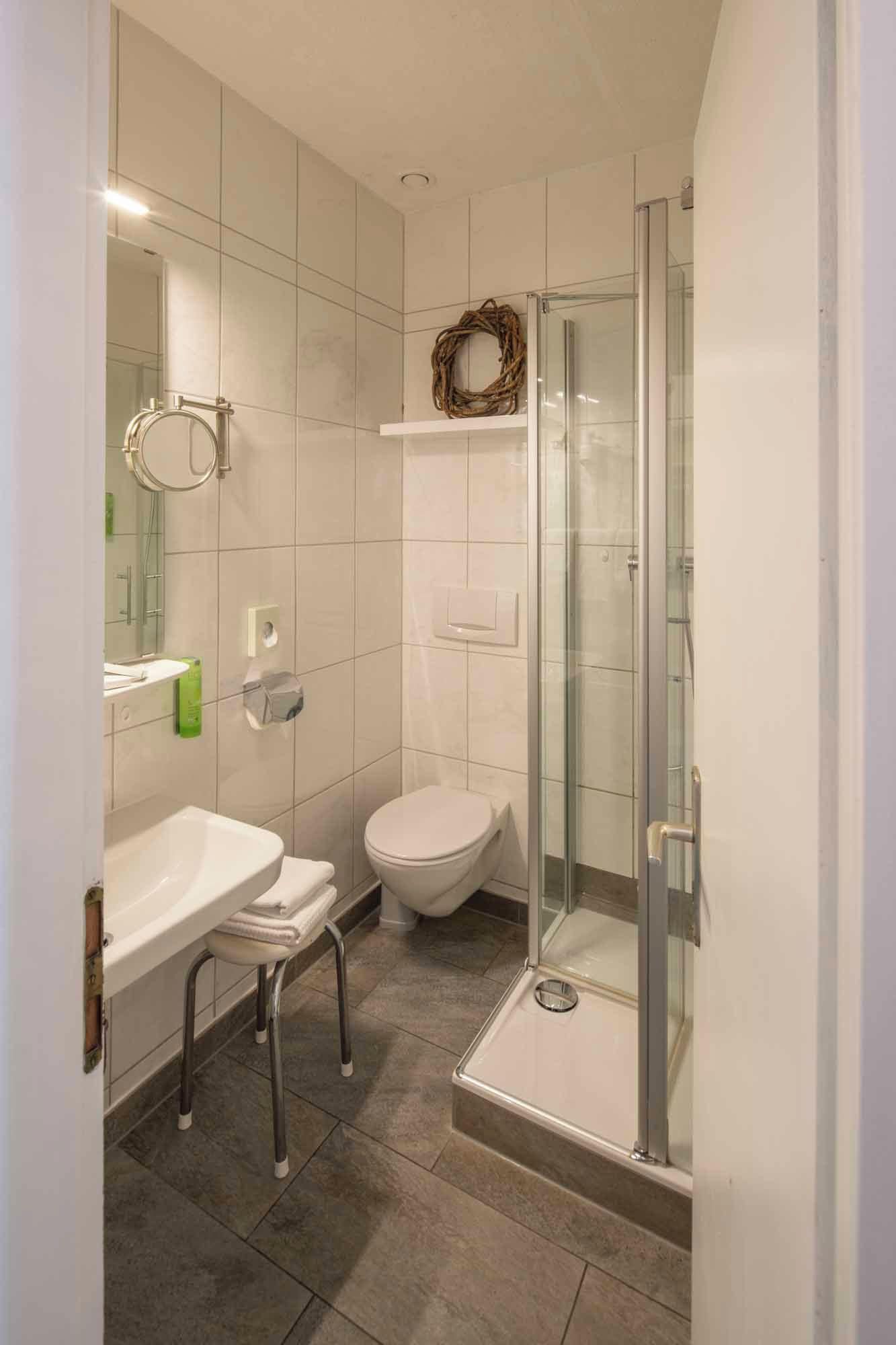 A modern bathroom with a glass shower enclosure, a white toilet, and a sink with a towel rack.