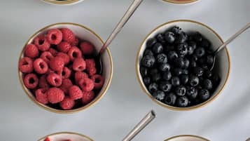 Six bowls of various fruits on a table.