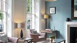 A modern living room with a fireplace, large windows, and a cozy seating area. - Montagu Place Hotel (London)