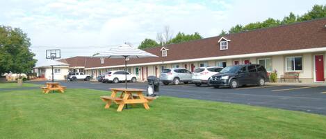 A motel with multiple parking spaces, picnic tables, and a basketball hoop.