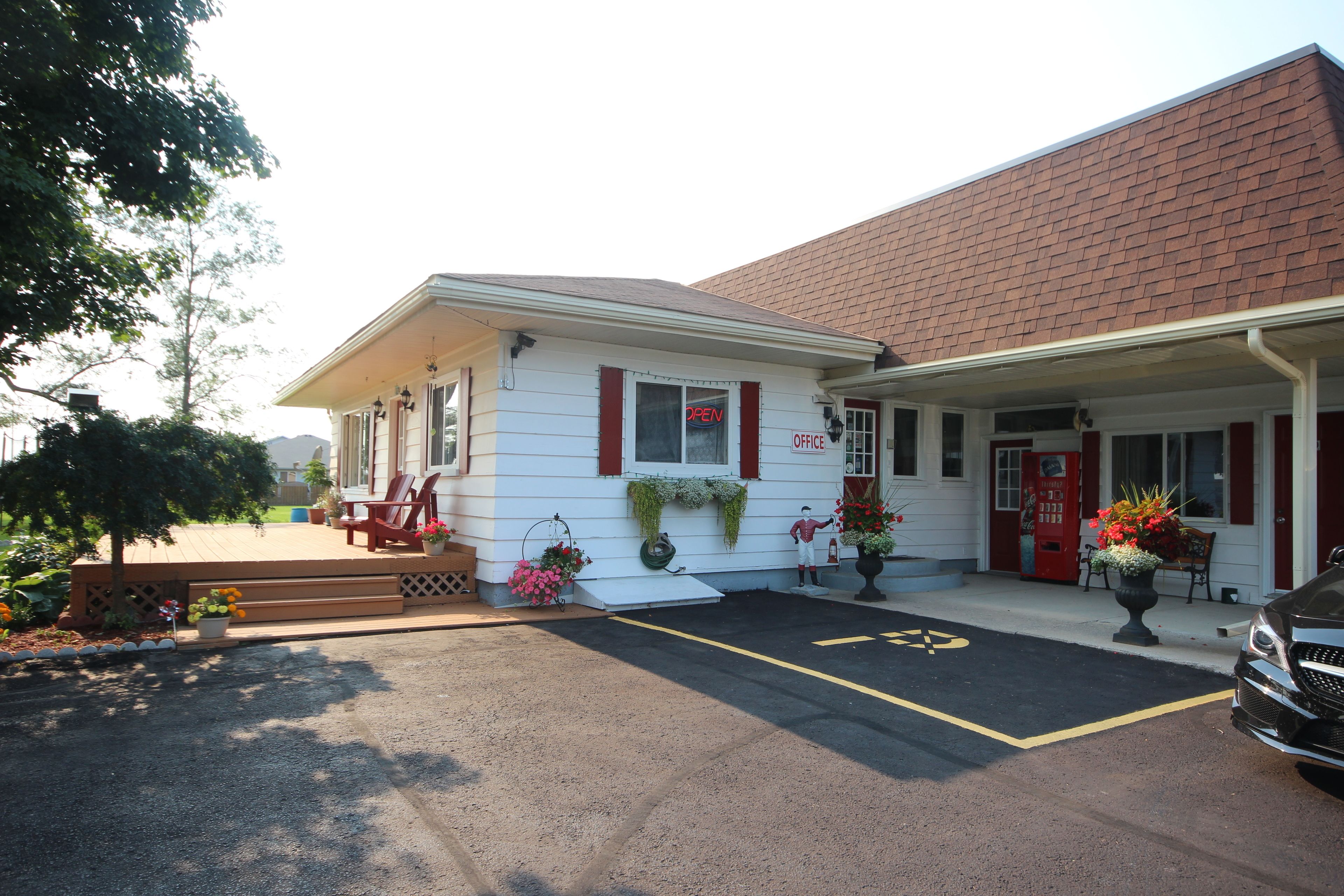 A two-story building with a red roof, a white facade, and a red door. There is a parking lot in front with a yellow handicapped parking space.