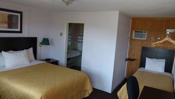 Une chambre d’hôtel avec deux lits, une armoire, un miroir, un bureau et un porte-manteau.