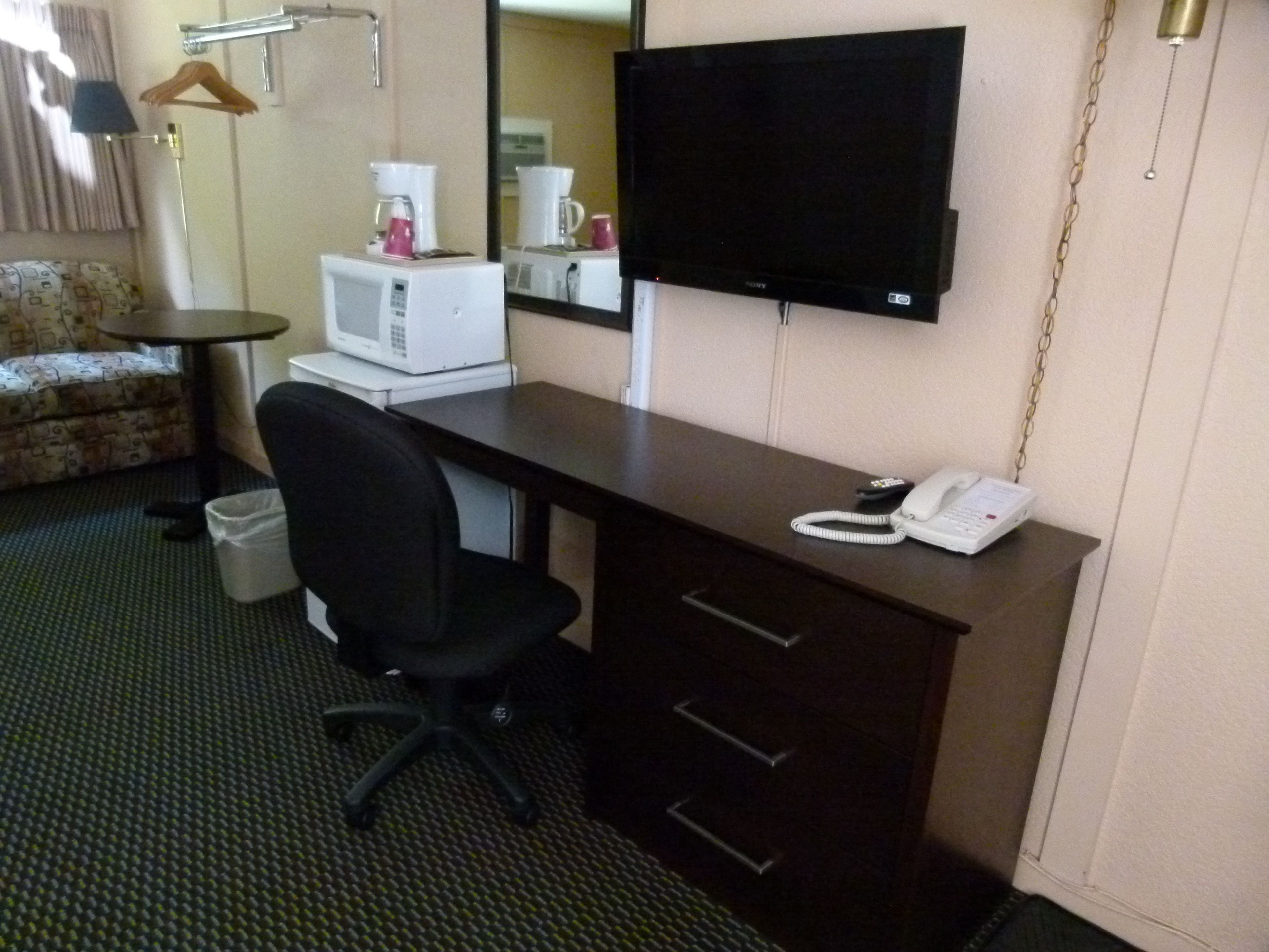 Une chambre d’hôtel équipée d’un bureau, d’une chaise, d’une télévision, d’une machine à café et d’un téléphone.