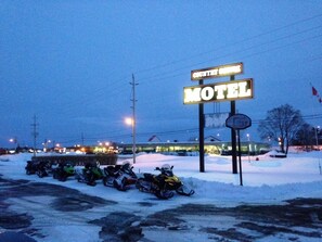 A motel sign with a snow-covered parking lot and snowmobiles. - Country Squire Motel (Arnprior)