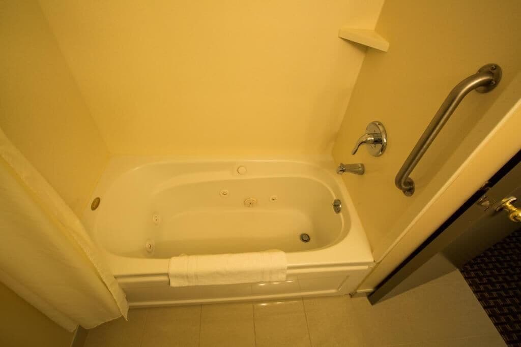 A standard hotel bathroom with a bathtub, a shower, and a handrail.
