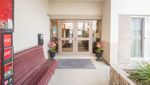 L’entrée d’un hôtel, avec un distributeur automatique de Coca-Cola rouge, un banc et des plantes en pot.