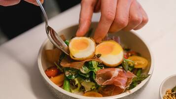 A bowl of salad with a hard-boiled egg, greens, and prosciutto.