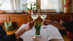 A dining table with two wine glasses, a candle, and a bowl of food. - Landhotel Hirschen (Oberwolfach)