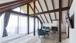 A hotel room with a large bed, a fireplace, a TV, and a dining area with chairs. - Best Western Hotel Polisina (Frickenhausen a. Main)