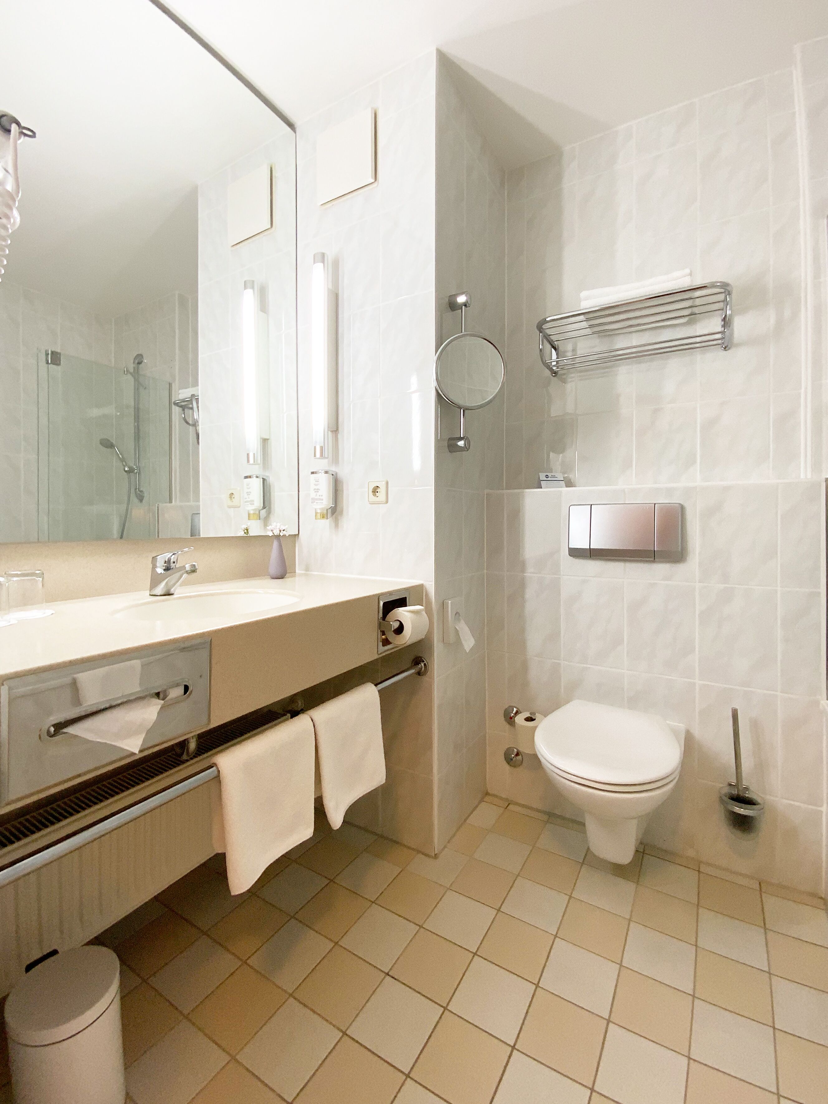 Ein modernes Badezimmer mit Waschbecken, Spiegel, Toilette und Dusche.