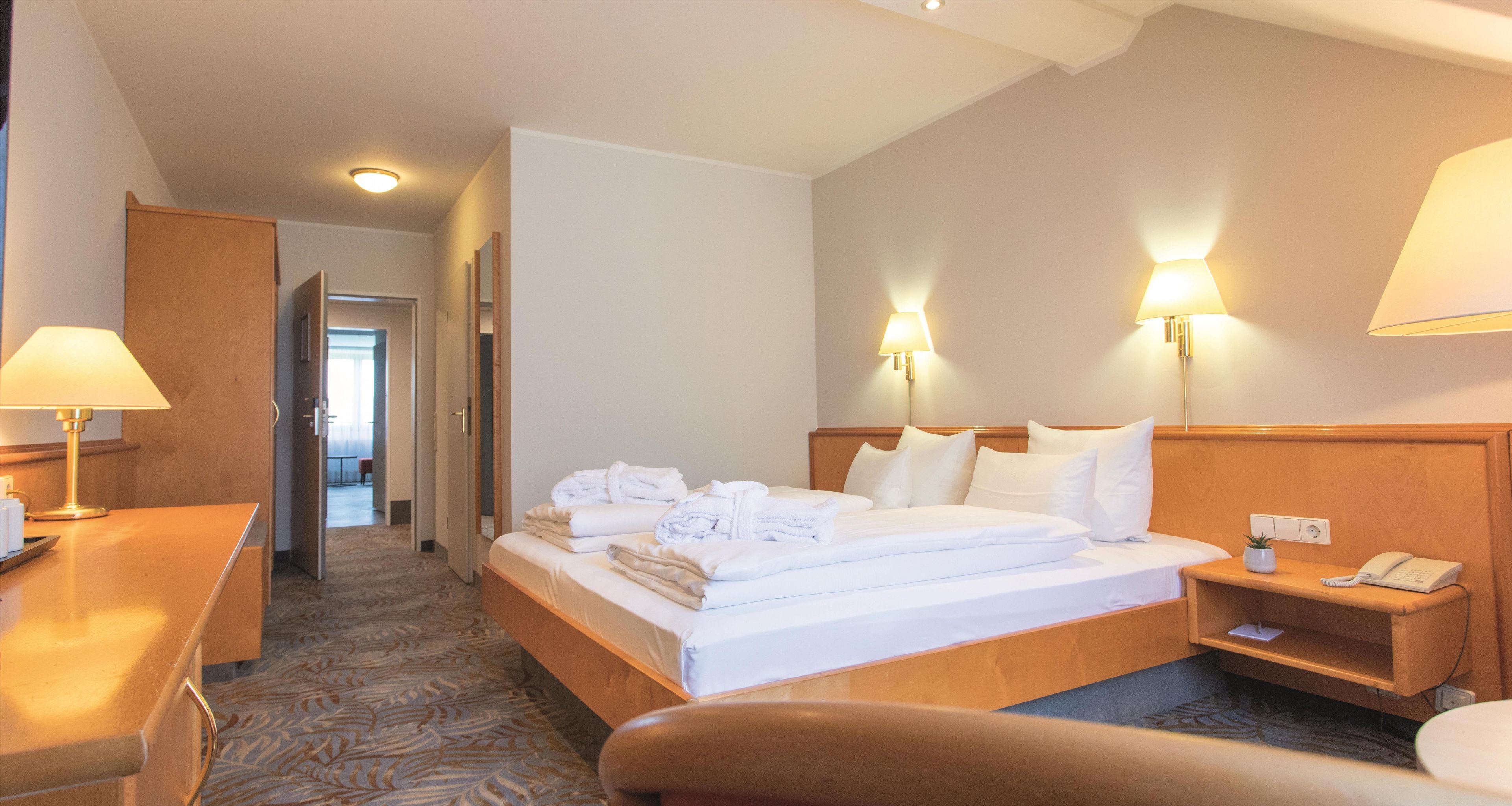 Une chambre d’hôtel avec un lit, des lampes de chevet, un bureau et une chaise.