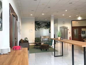A modern lobby with a wooden reception desk, seating area, and a large wall mural. - Best Western Hotel Polisina (Frickenhausen a. Main)