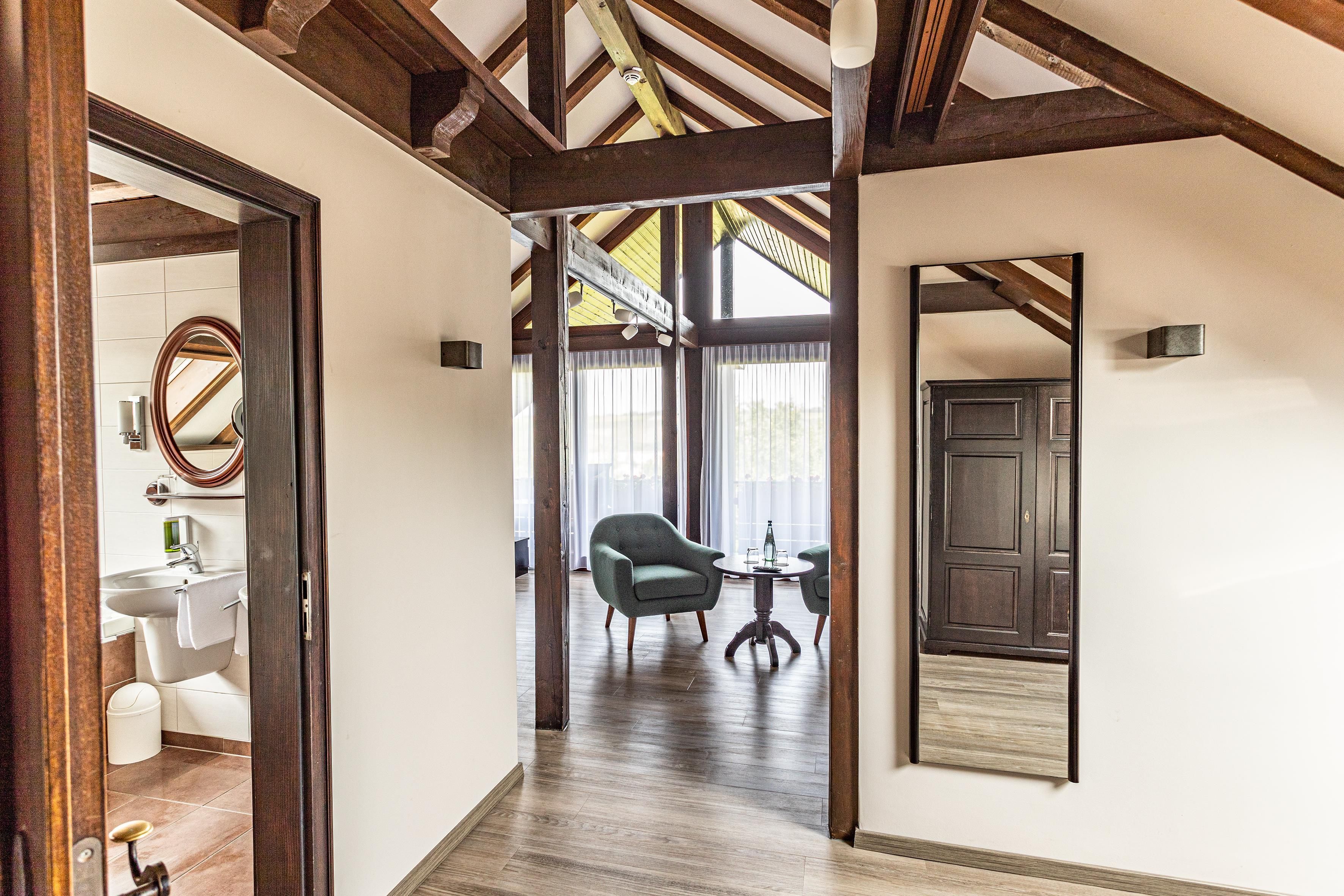 A hallway with wooden beams, a door, a mirror, and a chair.