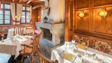 A dining area with wooden furniture, a fireplace, and a stone wall.