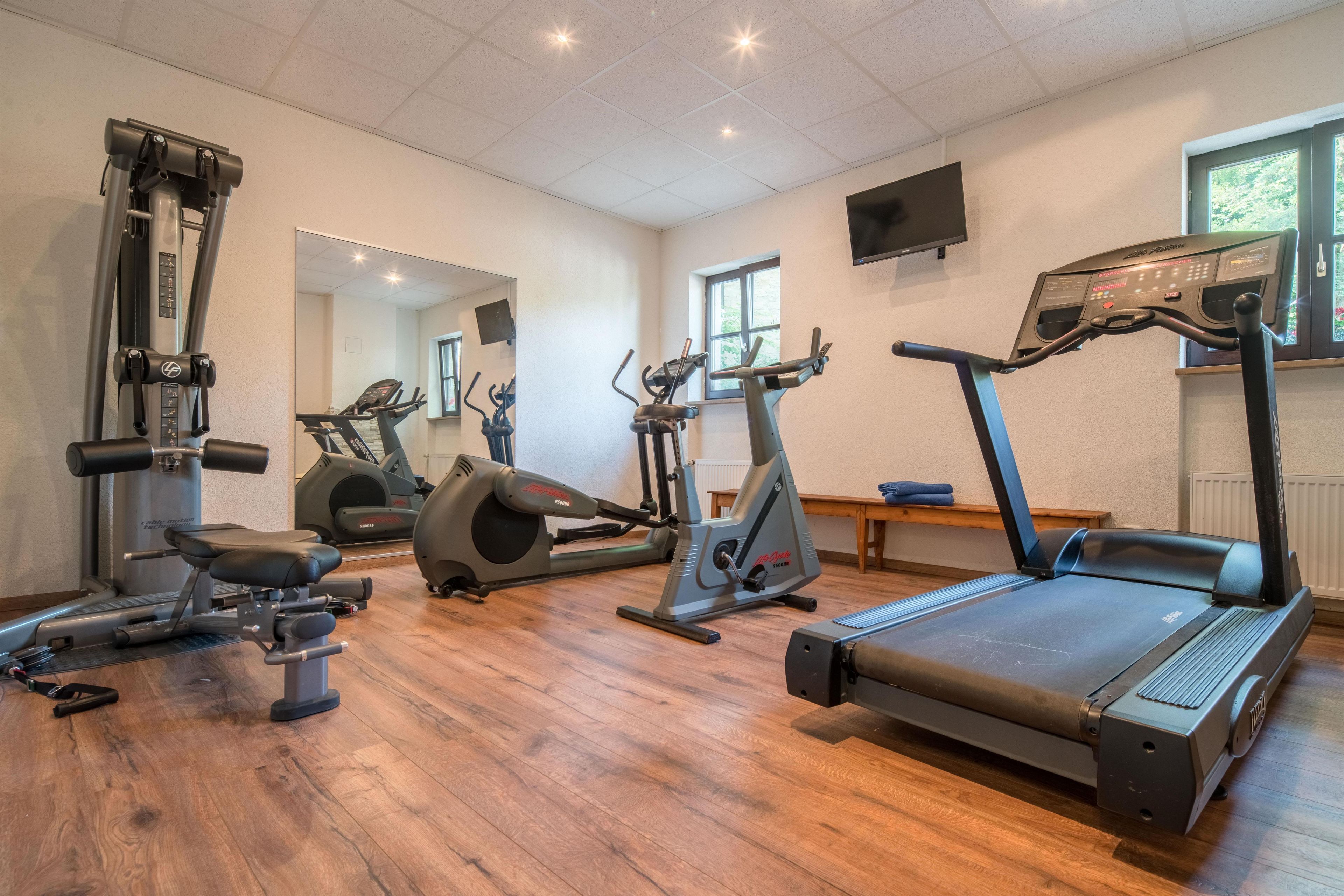 A gym with various exercise equipment including treadmills, stationary bikes, and weight machines.