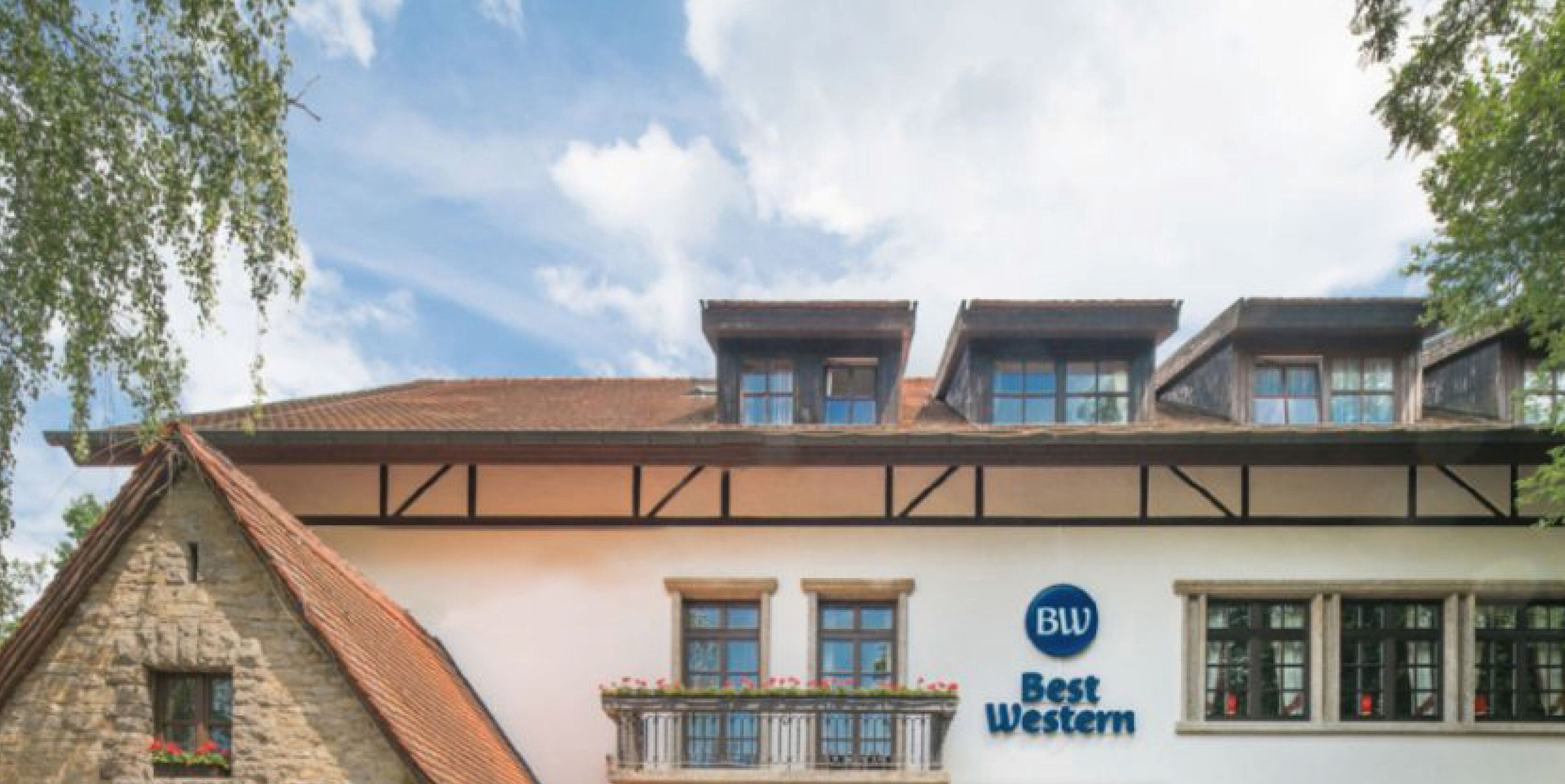 Un hôtel Best Western doté d’une façade en pierre, de nombreuses fenêtres et d’un balcon agrémenté de fleurs.