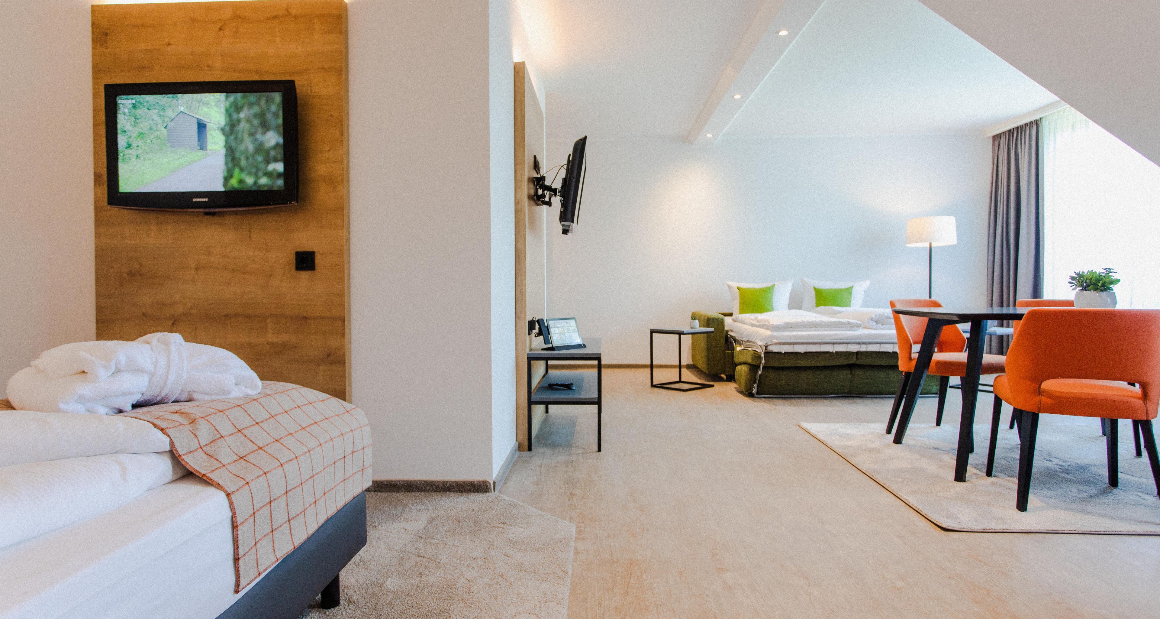 Une chambre d’hôtel équipée d’un lit, d’un bureau et d’un téléviseur fixé au mur.
