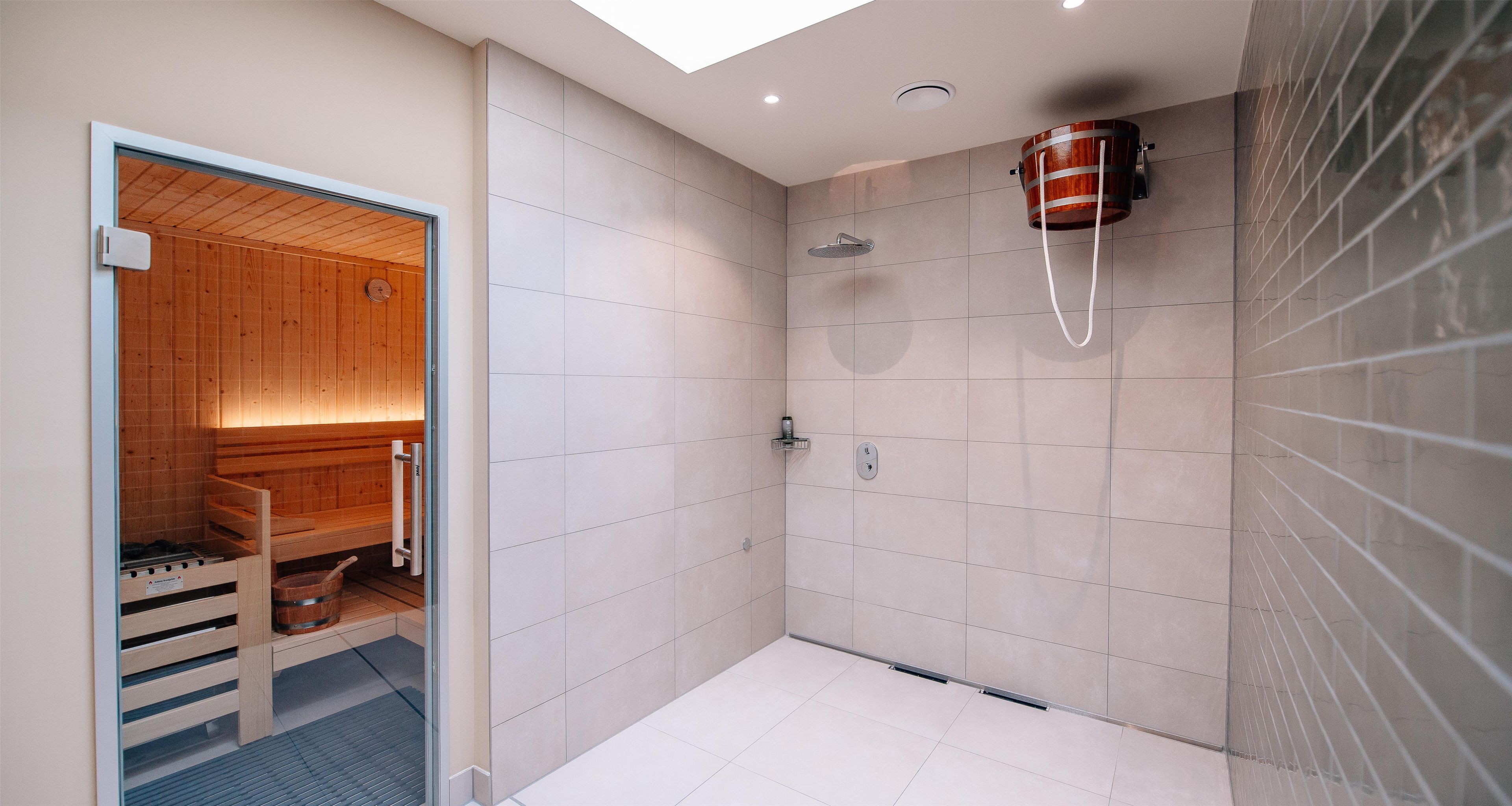 Un baño moderno con ducha, sauna de madera y un amplio ventanal.