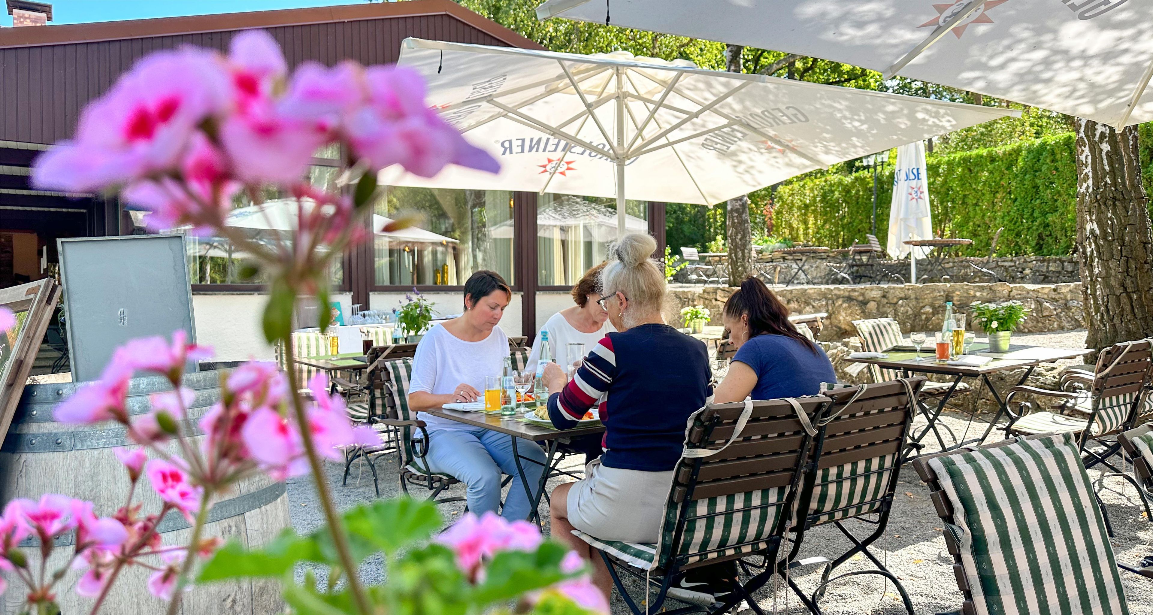 An outdoor seating area with tables and chairs, umbrellas, and a building in the background.