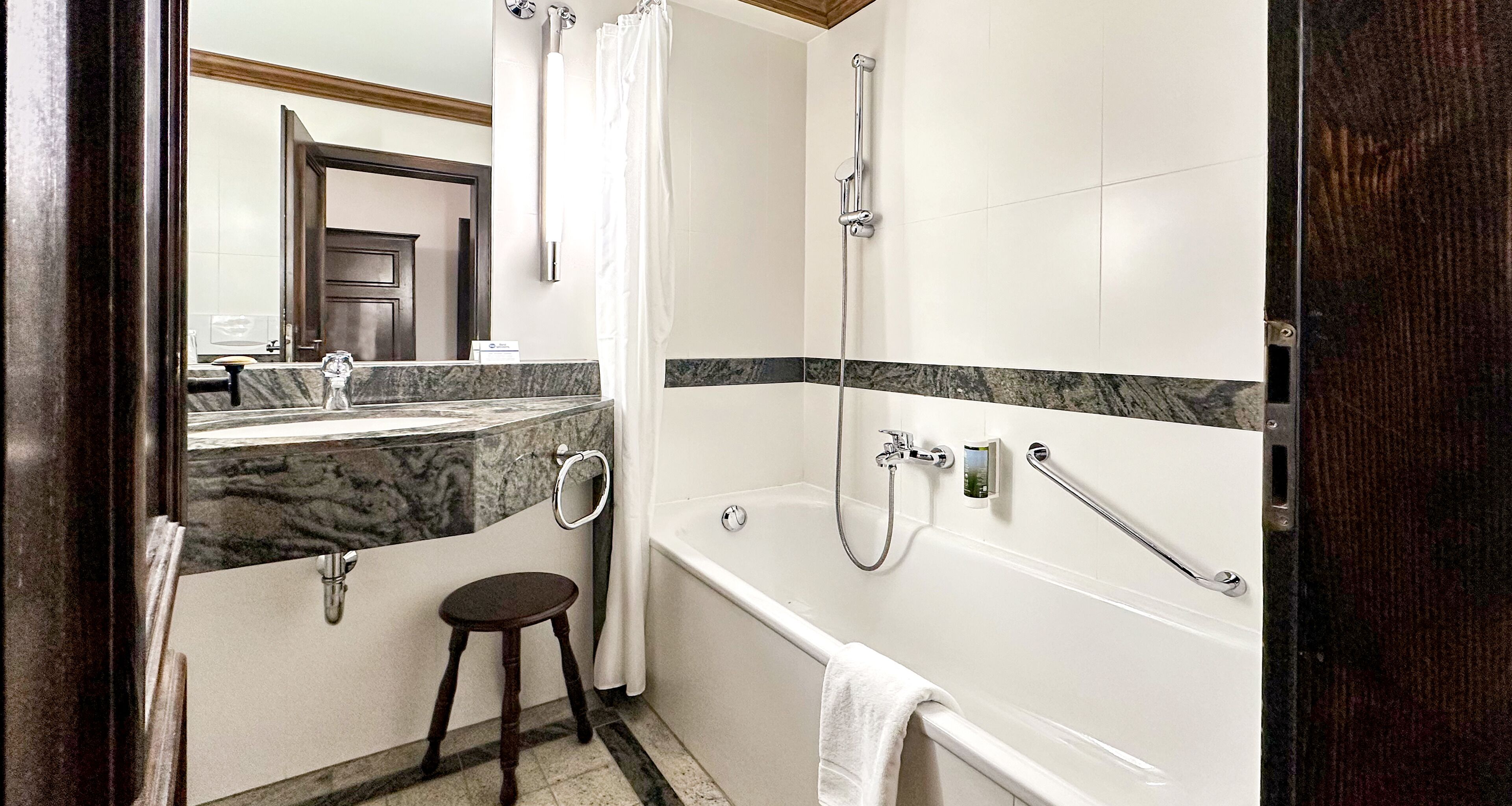 Une salle de bain avec une baignoire, une douche et un petit tabouret.