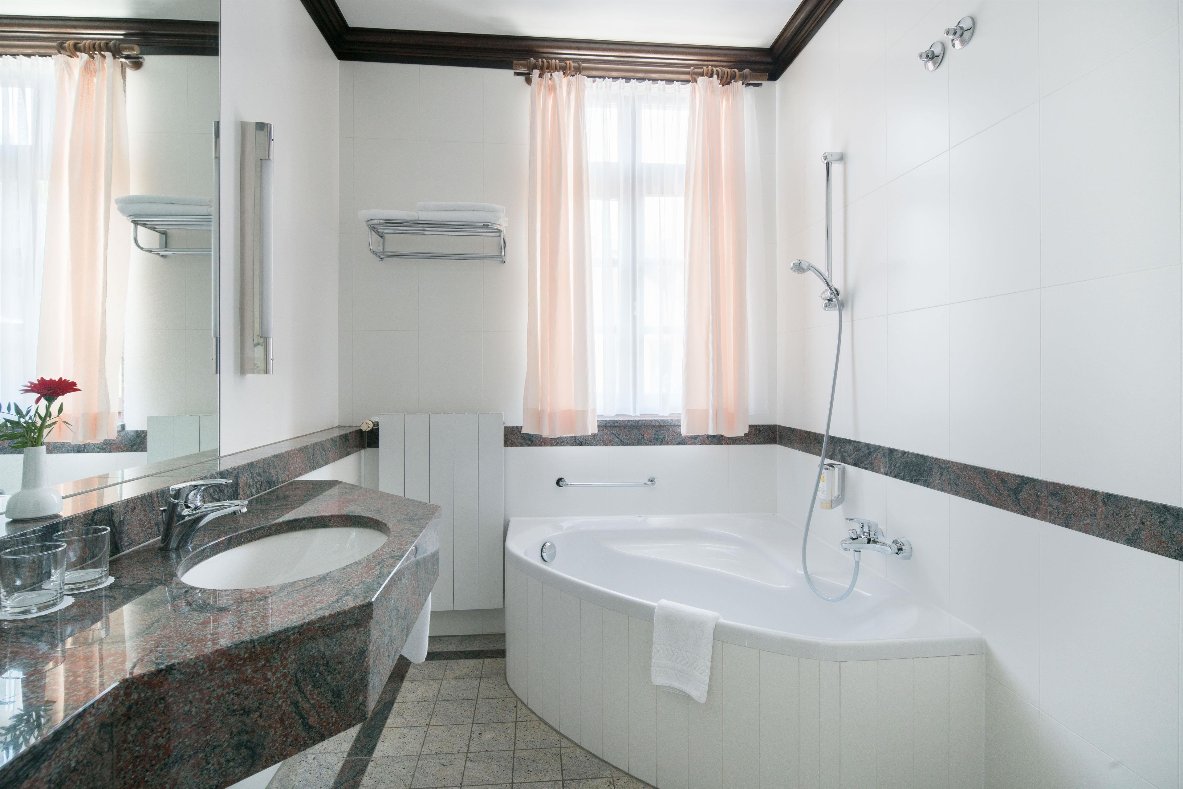 A modern bathroom with a double sink, a bathtub, and a shower.