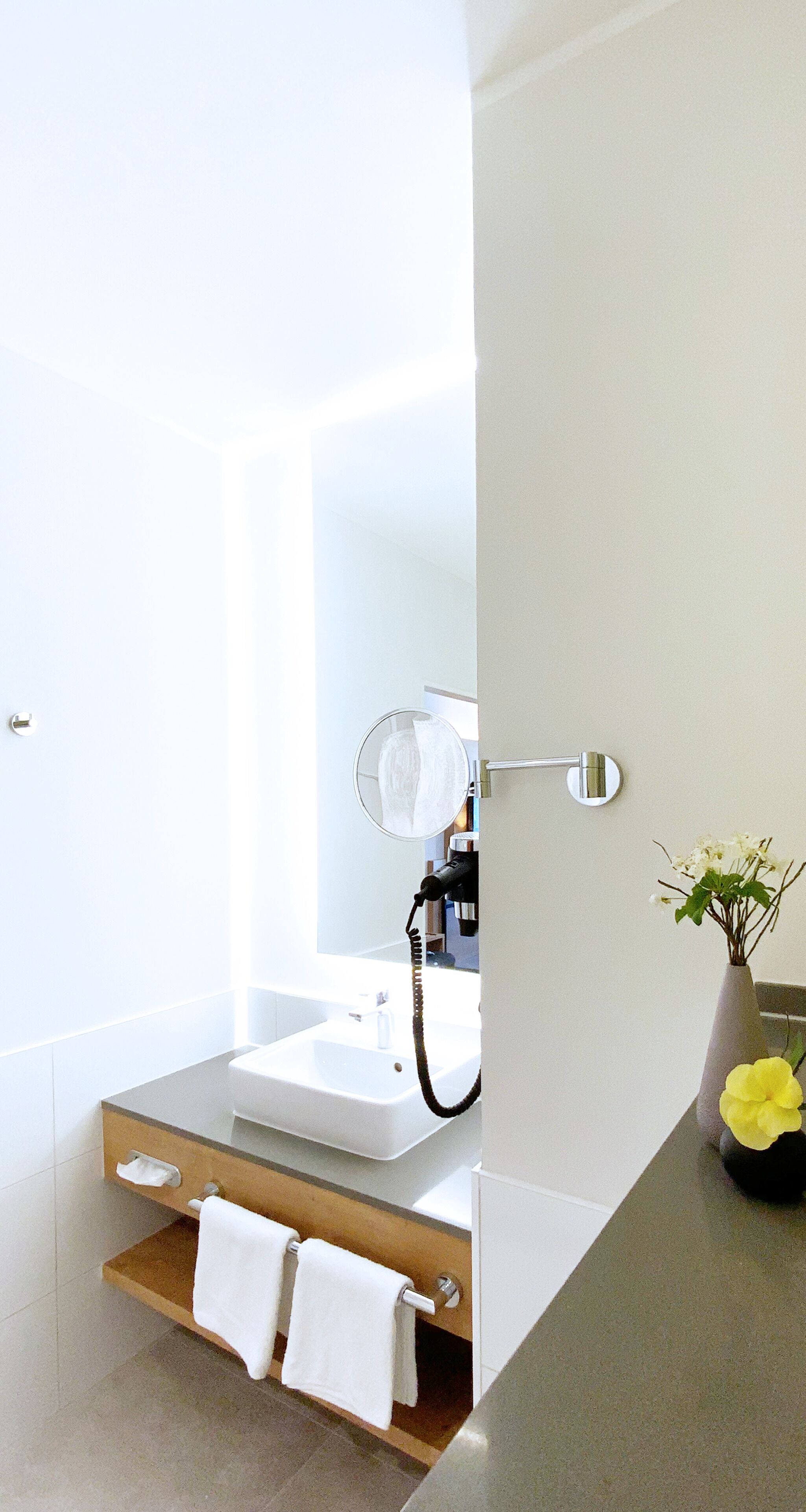 A modern bathroom with a white sink, a mirror, and a towel rack.