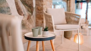 A round table with three ceramic cups and a small potted plant. A wicker chair is in the background.