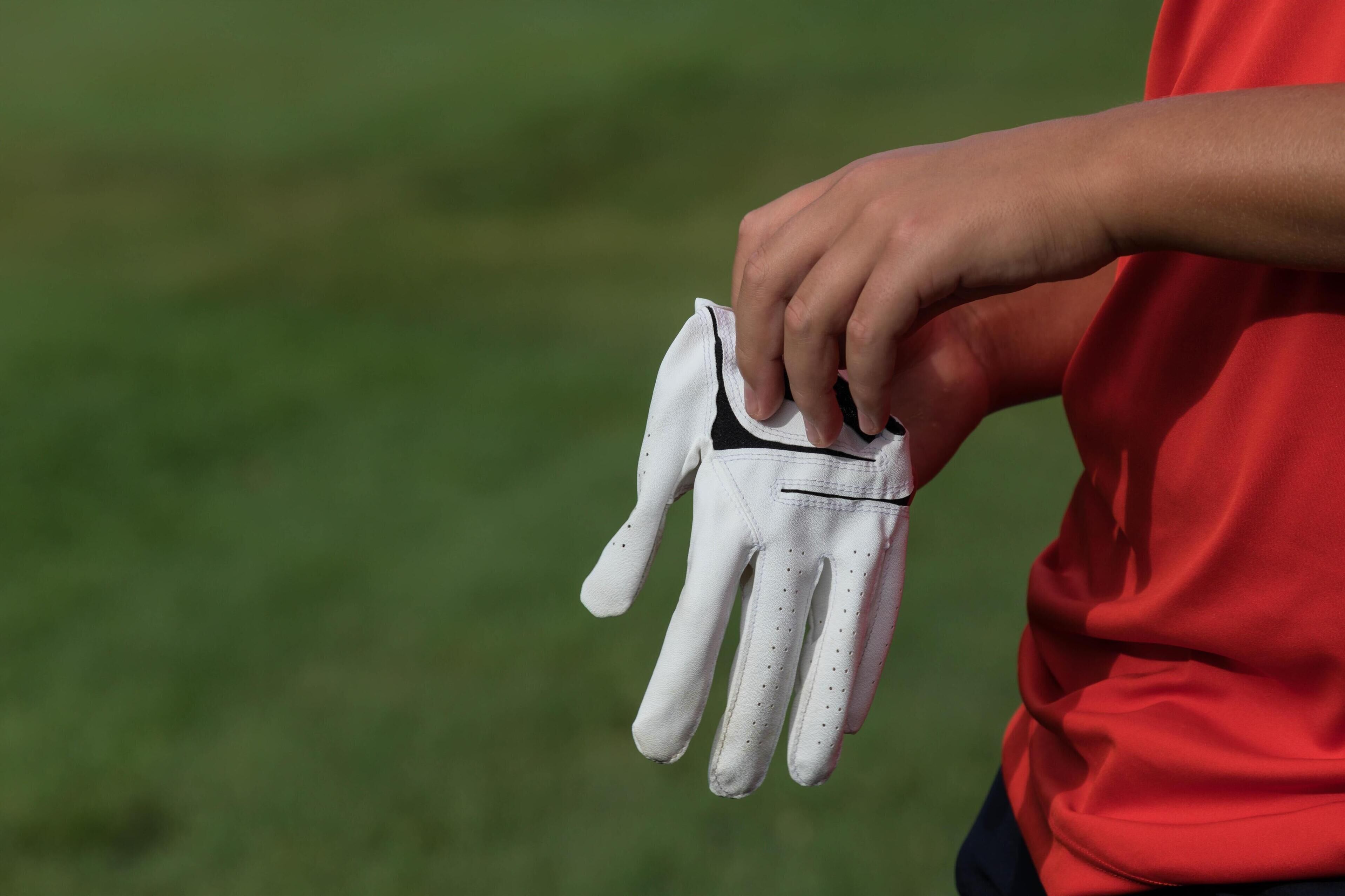 Eine Person hält einen weißen Golfhandschuh.