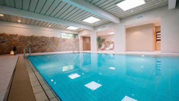 Una piscina techada, sillones reclinables de piscina
