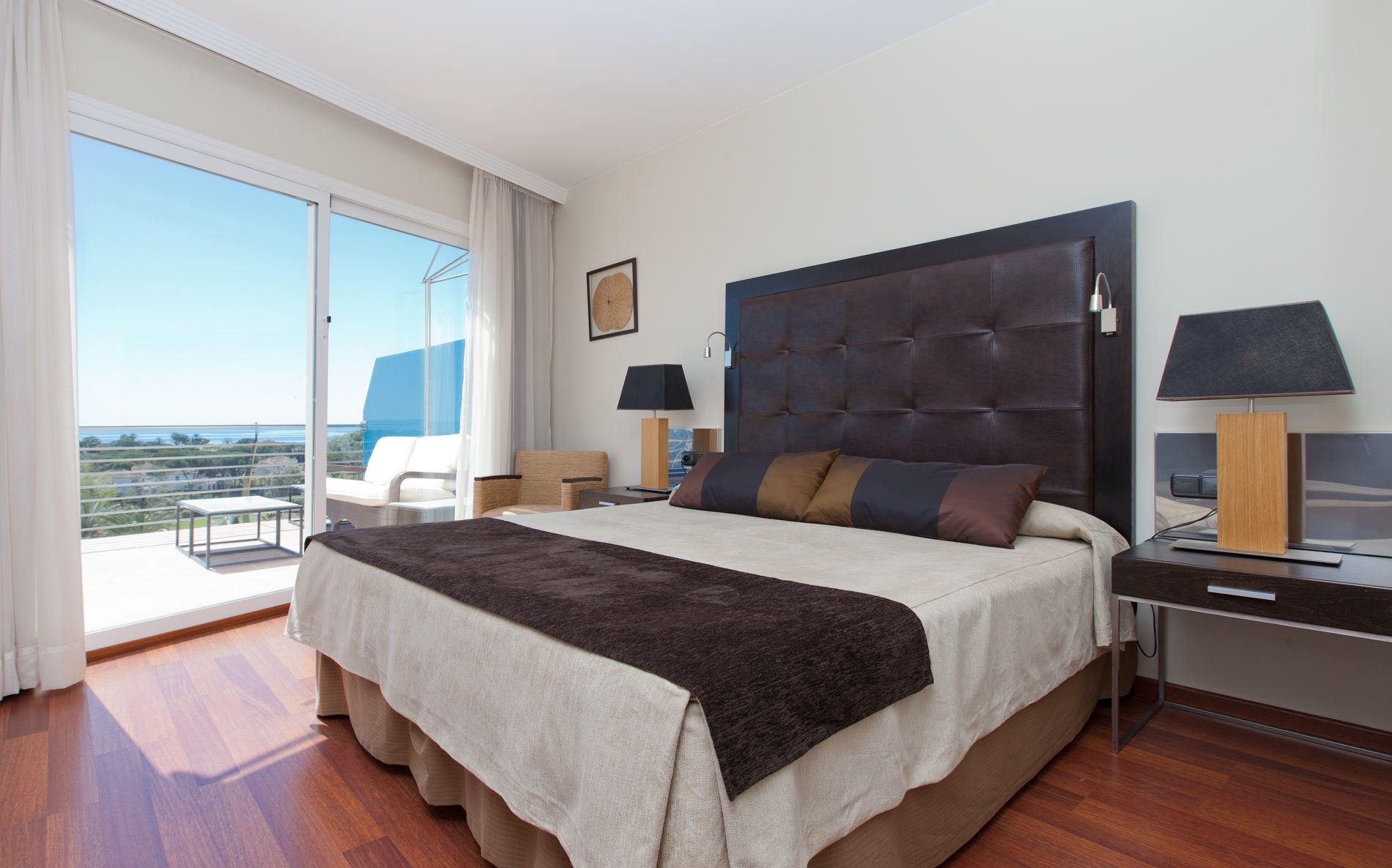 A spacious bedroom with a large bed, a balcony with a view, and a modern design.