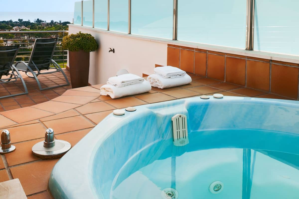 A rooftop terrace with a hot tub, lounge chairs, and a view of the city.
