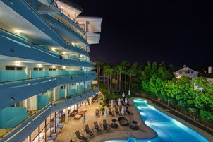 Een hotel met meerdere verdiepingen, een zwembad, terras en een goed verlicht balkon.