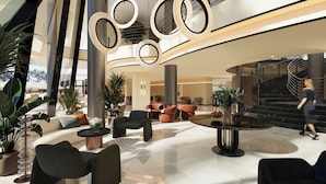 A modern lobby with a central seating area, a staircase, and a large mirror.