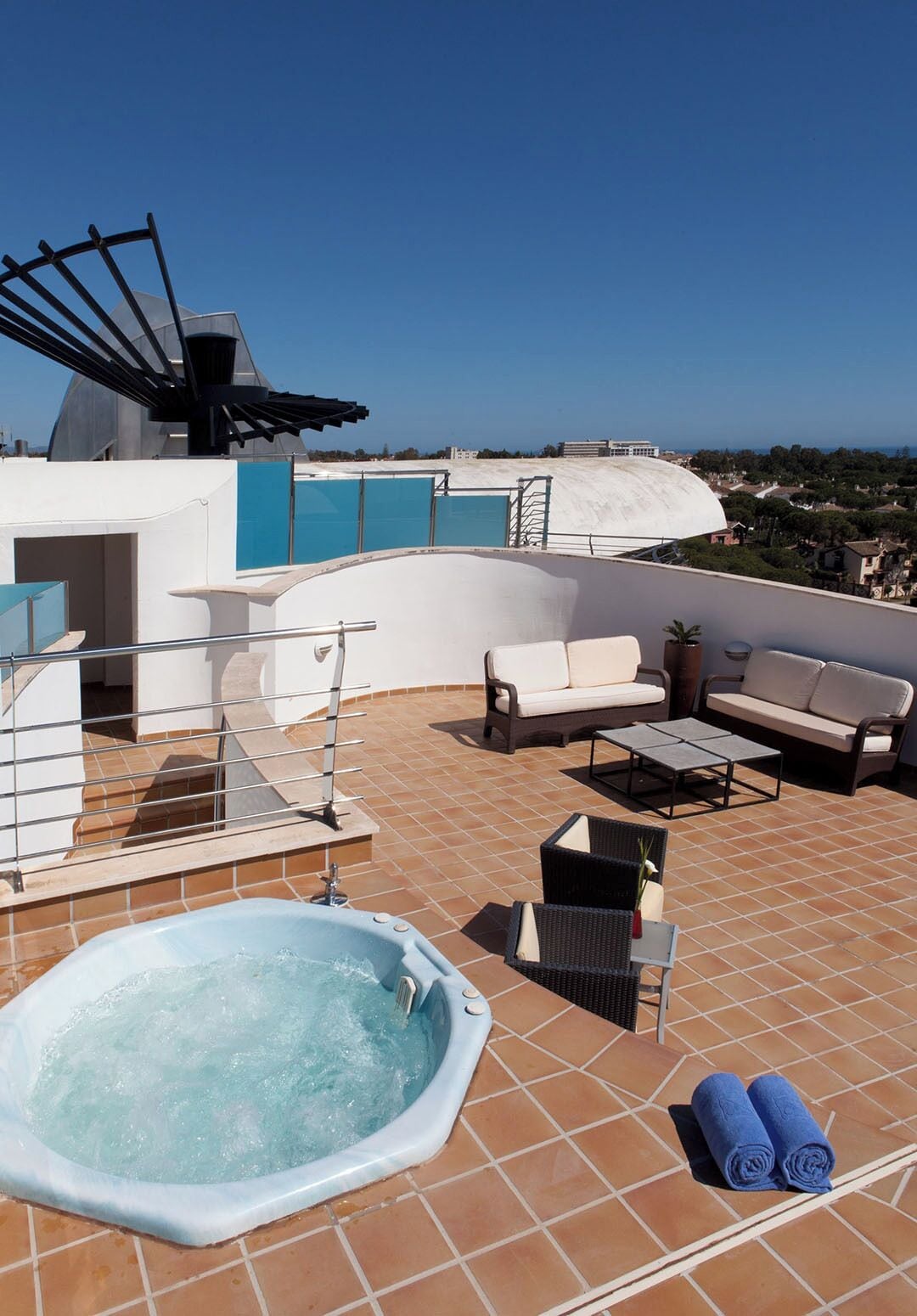 Une terrasse sur le toit avec un jacuzzi, des sièges extérieurs et une vue sur la mer.