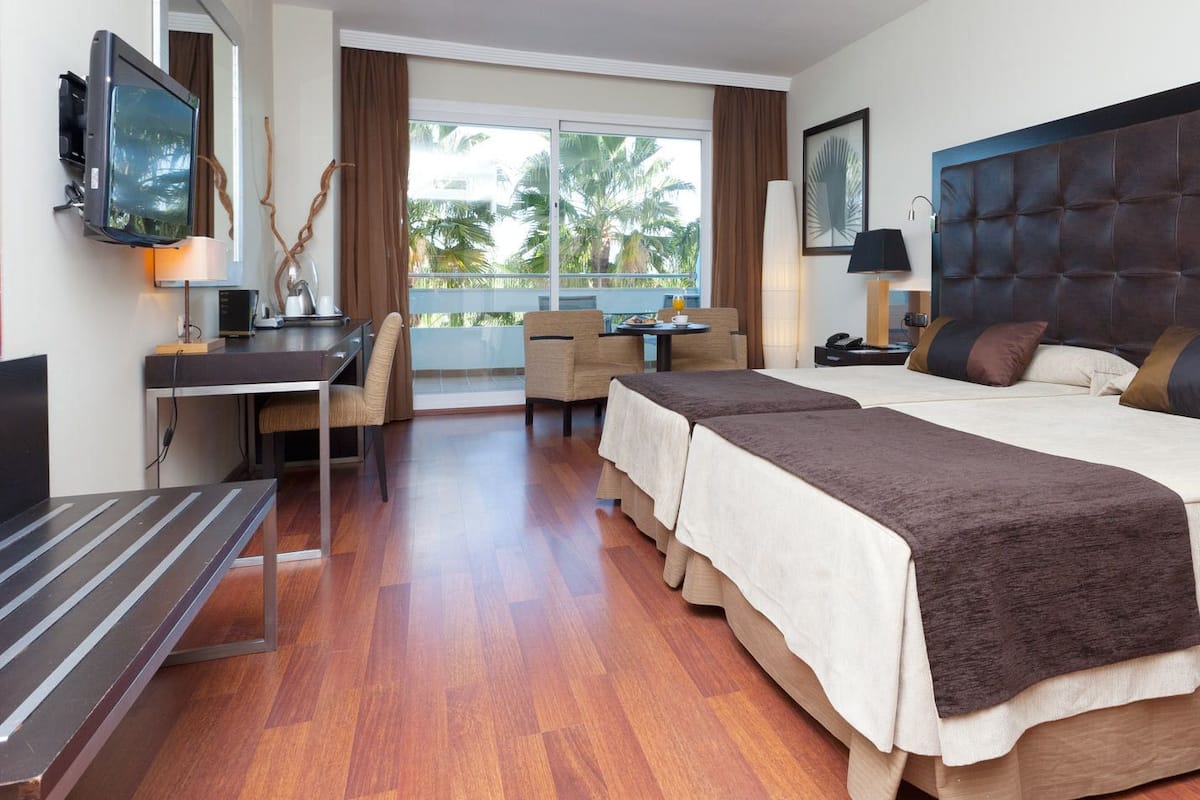 A hotel room with a large bed, a desk, a chair, and a TV.