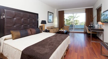 Hotelkamer met een groot bed, een bureau, een stoel, een televisie en een balkon met uitzicht.