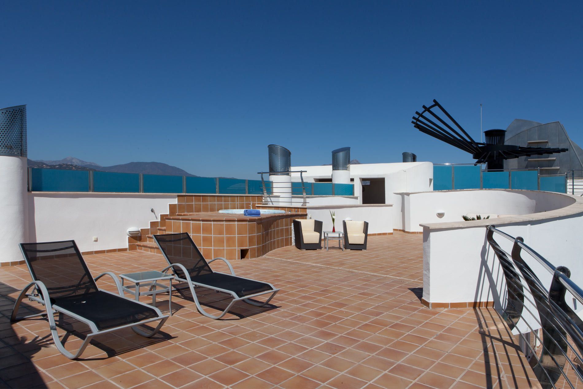 A rooftop terrace with outdoor seating, a hot tub, and a view of the sea.