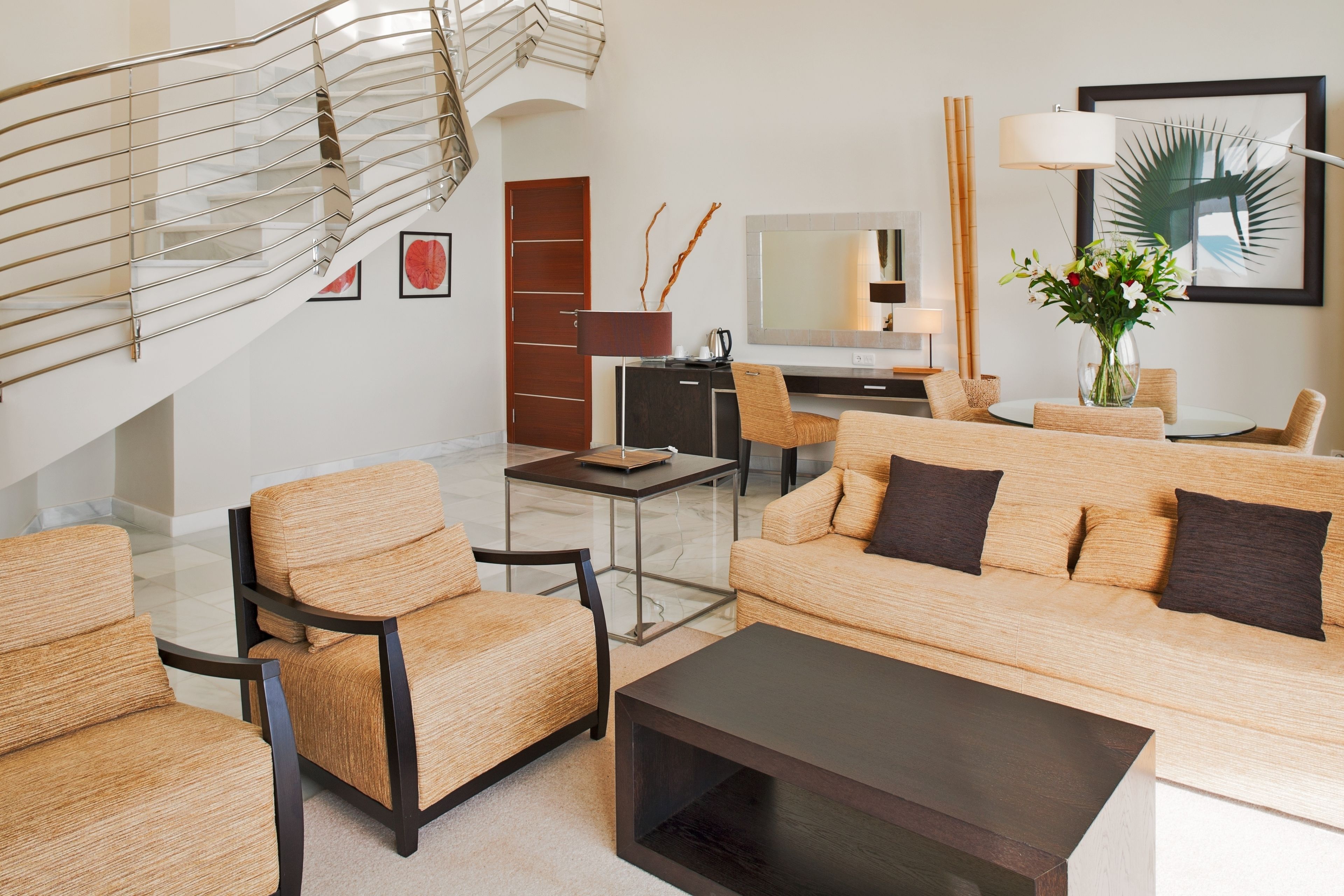 Una sala moderna con una escalera, un conjunto de sofá, una mesa de centro, un escritorio y un televisor.